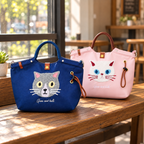 Dark blue and blush pink cat bag color options on a wooden cafe bench; bags sold individually