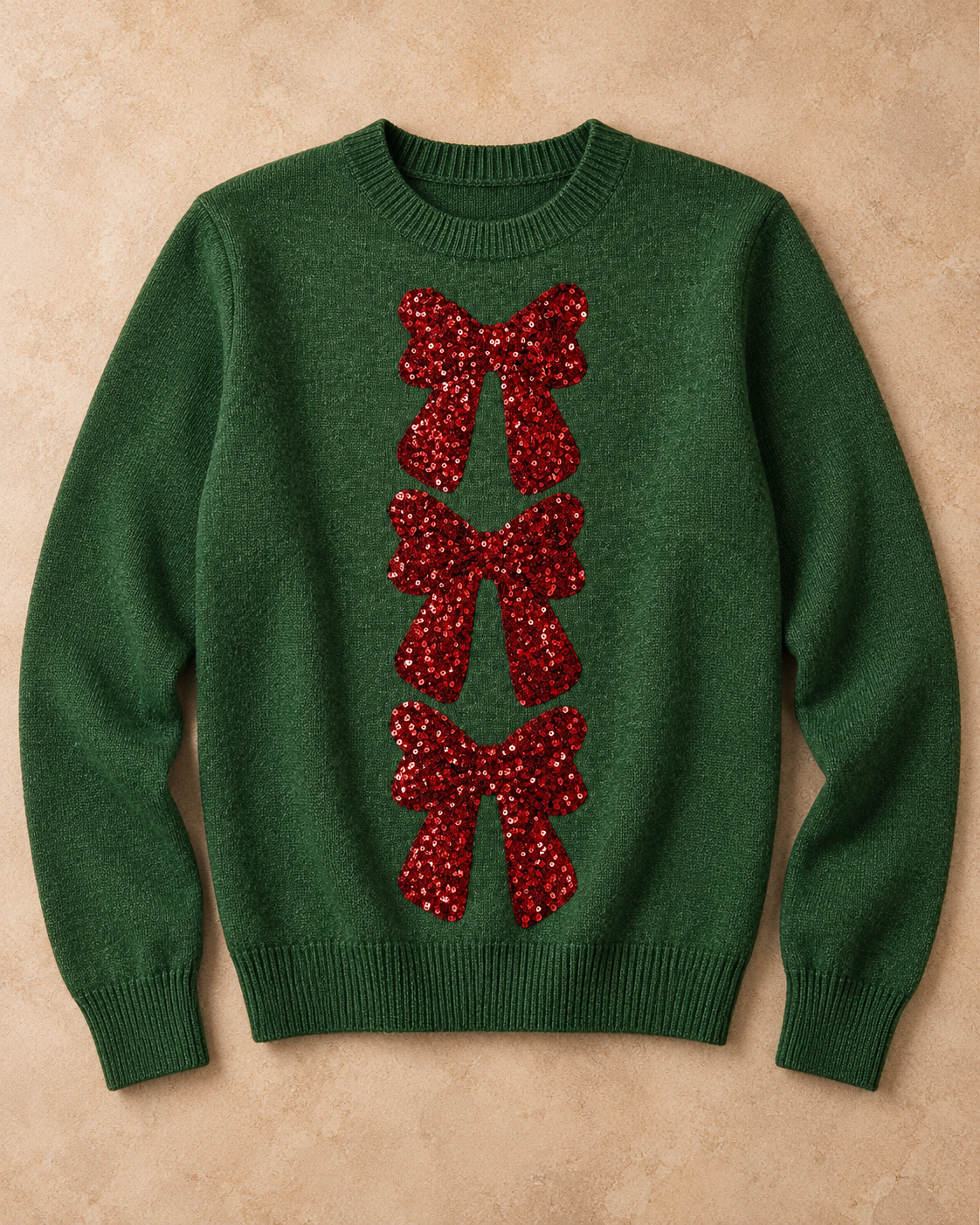 SO ME Holiday Bow Sequin Sweater in Hunter Green with three red sequin bows, laid on warm beige stone.